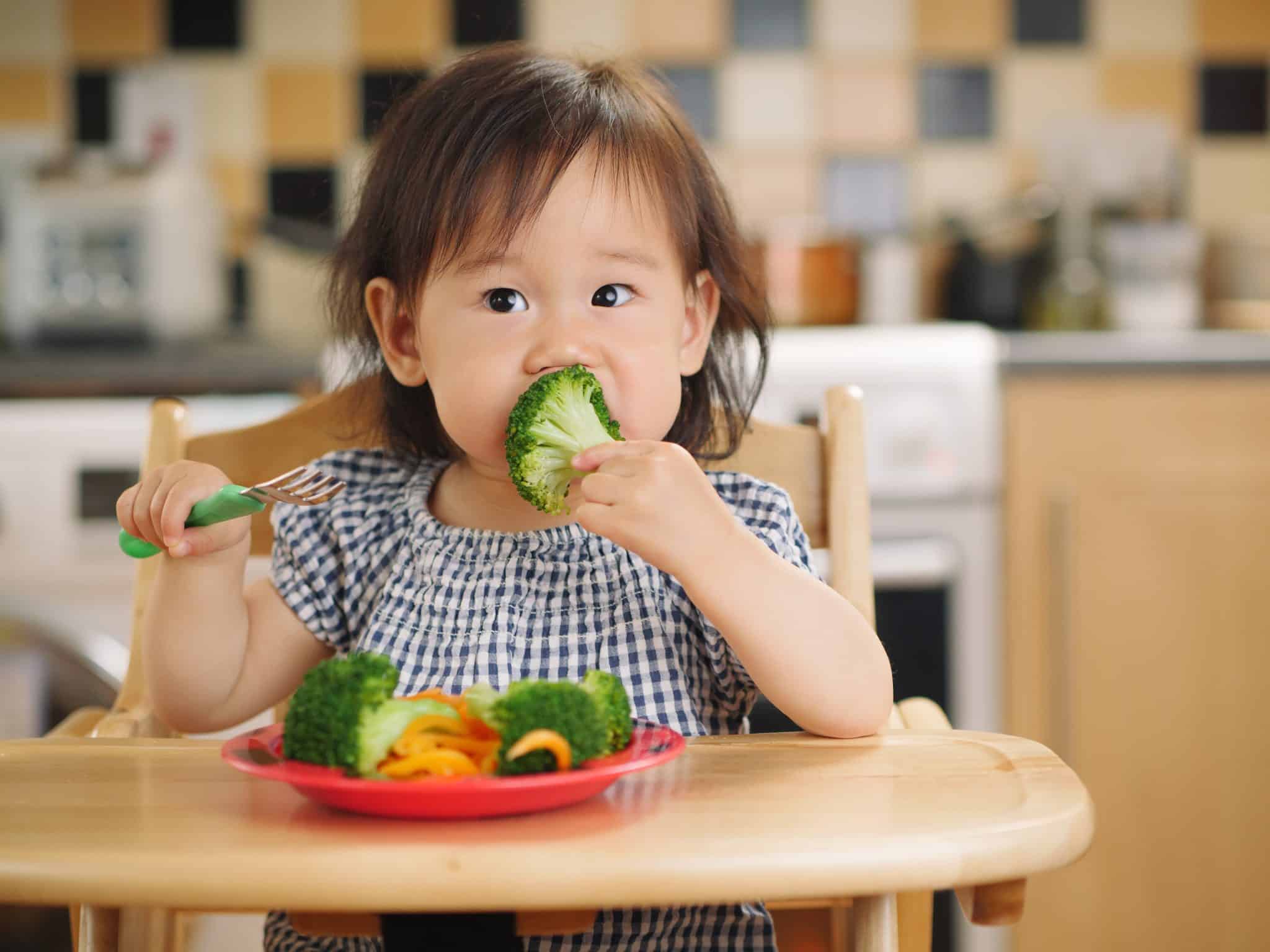 a toddler eating vegetables